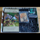 Board game components including a book, cards, and miniatures in an open box.
