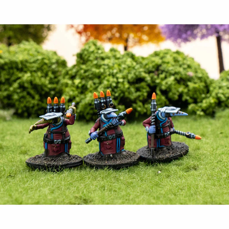 Three miniature figures with futuristic weapons on grass with blurred foliage in the background