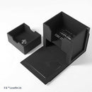 Black card game box with carbon fiber texture and visible branding on a white background