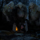 Three large stone statues in a dark, forested area with a small figure standing before them.