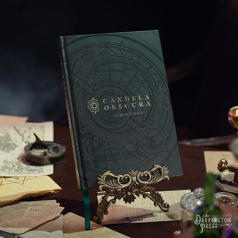 Dark blue book titled 'Candela Obscura' on a desk with vintage items.