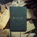 Dark blue book titled 'Candela Obscura' surrounded by old papers and mystical symbols on a dark background