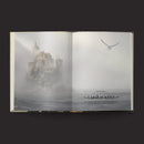 Open book with a foggy landscape and castle on the left page, and a bird in flight on the right page.
