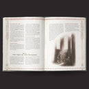 Open book with text and a black and white illustration on a dark background