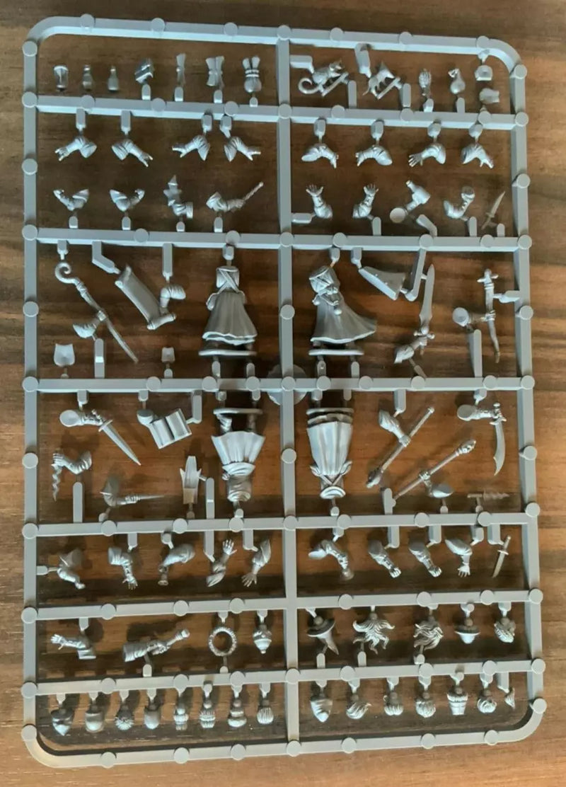 Plastic model parts on a tray with various small figures and accessories on a wooden surface