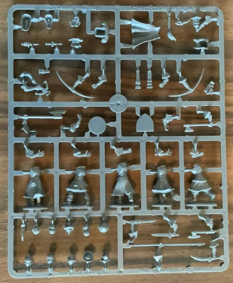 Plastic model kit components on a clear plastic sheet with a wooden background