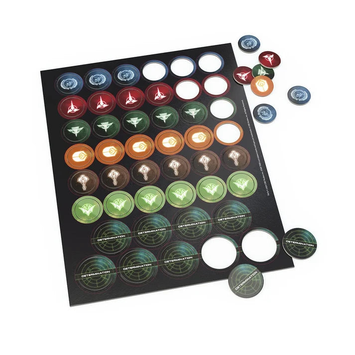 A board game component set featuring a black rectangular board with circular colored tokens arranged in rows, plus several loose tokens scattered around on a white background.
